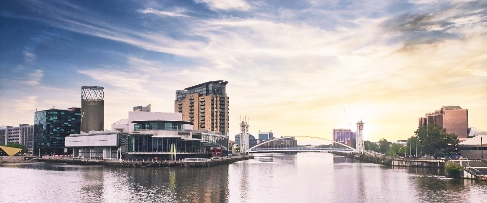Modern glass buildings and old brick factories facing the River Irwell in central Manchester.